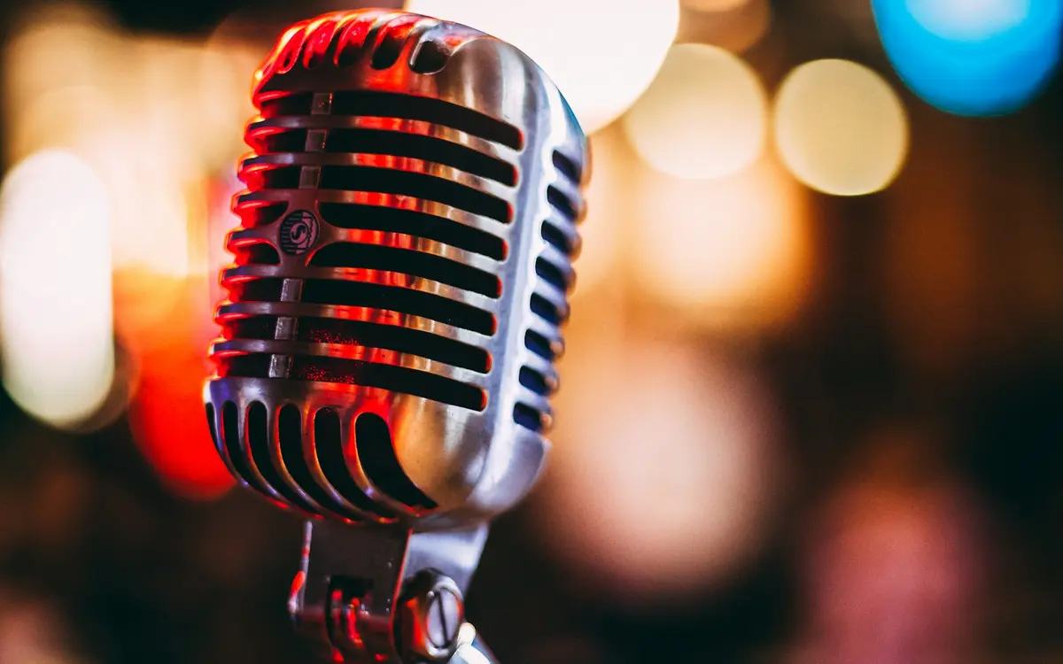 Comedian mit Mikrofon auf der Bühne vor Publikum