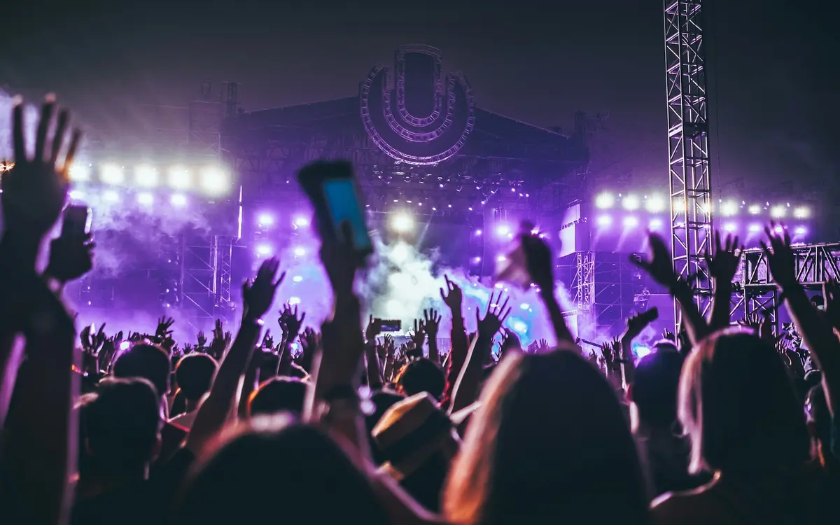 Besucher bei einem Festival mit bunter Bühnenbeleuchtung